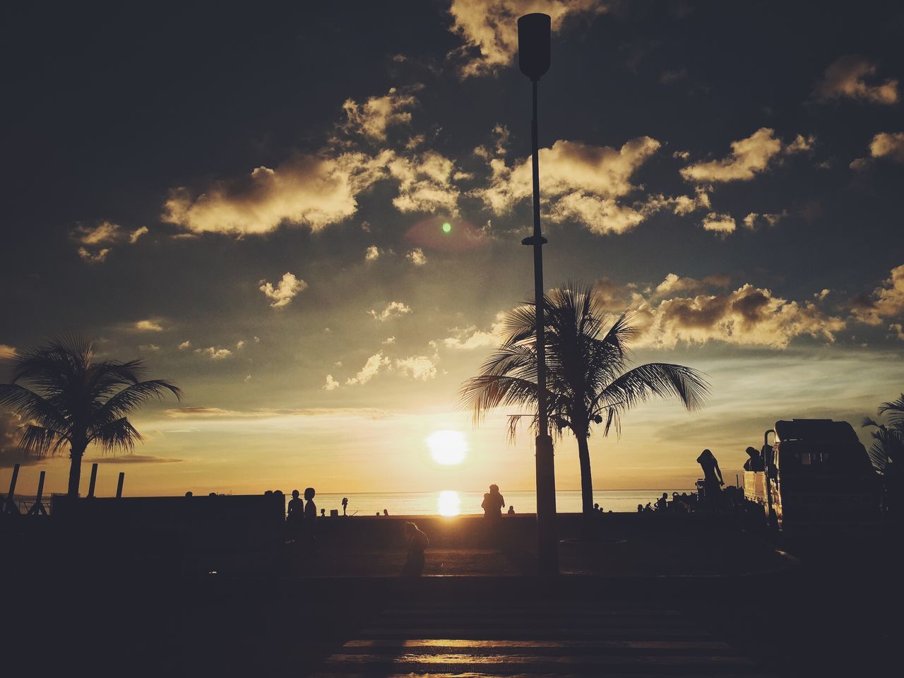 sunset, silhouette, sky, tree, tranquility, cloud - sky, palm tree, scenics, tranquil scene, beauty in nature, sun, nature, street light, cloud, sunlight, idyllic, outline, tree trunk, orange color, sea