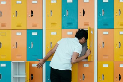 Rear view of young man looking in lockers