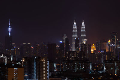 Illuminated modern cityscape against sky at night