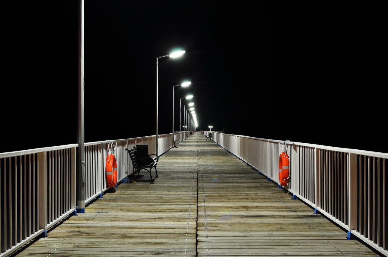 WALKWAY LEADING TO ILLUMINATED STREET LIGHT AT NIGHT