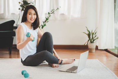 Young woman using phone while sitting at home