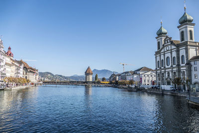 River amidst buildings in city against clear blue sky