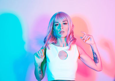 Portrait of young woman standing against illuminated background