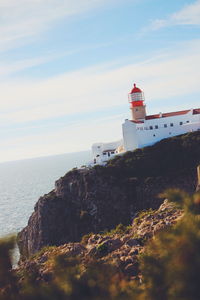 Lighthouse by sea against sky