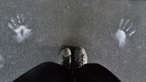 Low section of person standing by handprints on floor