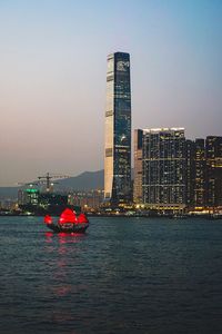 Modern buildings at victoria harbour in city during sunset