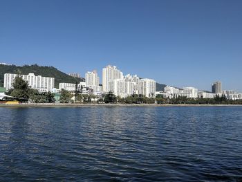 Sea by buildings against clear blue sky