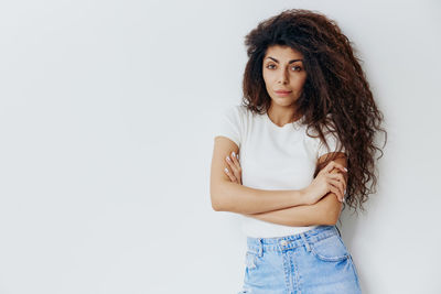 Portrait of young woman standing against white background