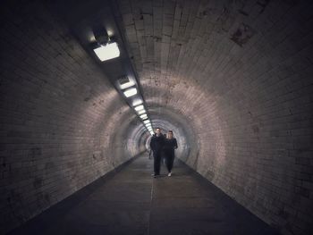 Rear view of man walking in subway tunnel