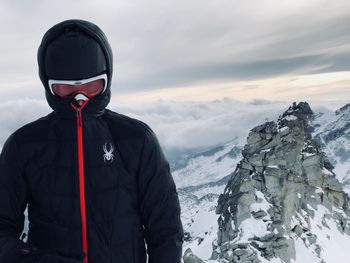 Man standing on mountain peak against sky during winter