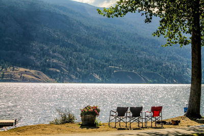 Chairs and table by lake against mountains