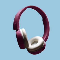 Modern wireless headphones in purple color on an isolated pastel blue background. the concept of