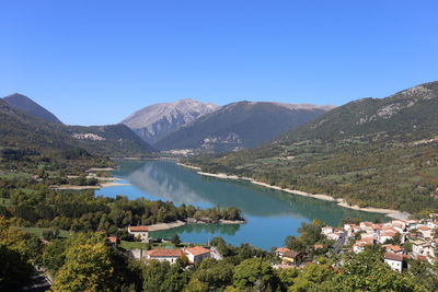 Scenic view of lake and mountains against clear blue sky