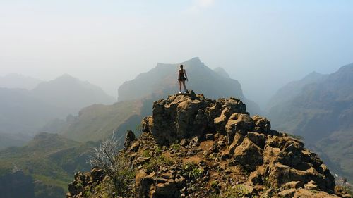 Rear view of man standing on mountain against sky