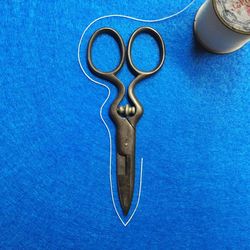 Close-up of scissors and thread on blue surface