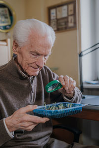 Smiling man holding seedlings in tray at home