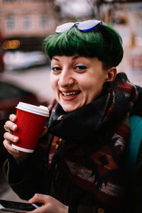 Portrait of happy non-binary hipster woman drinking coffee in city