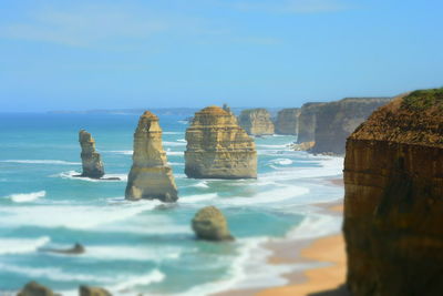 Rock formations in sea against clear blue sky