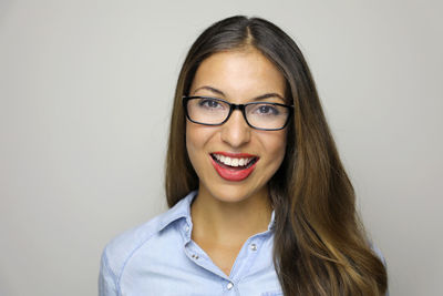 Close-up portrait of cheerful woman wearing eyeglasses against gray background