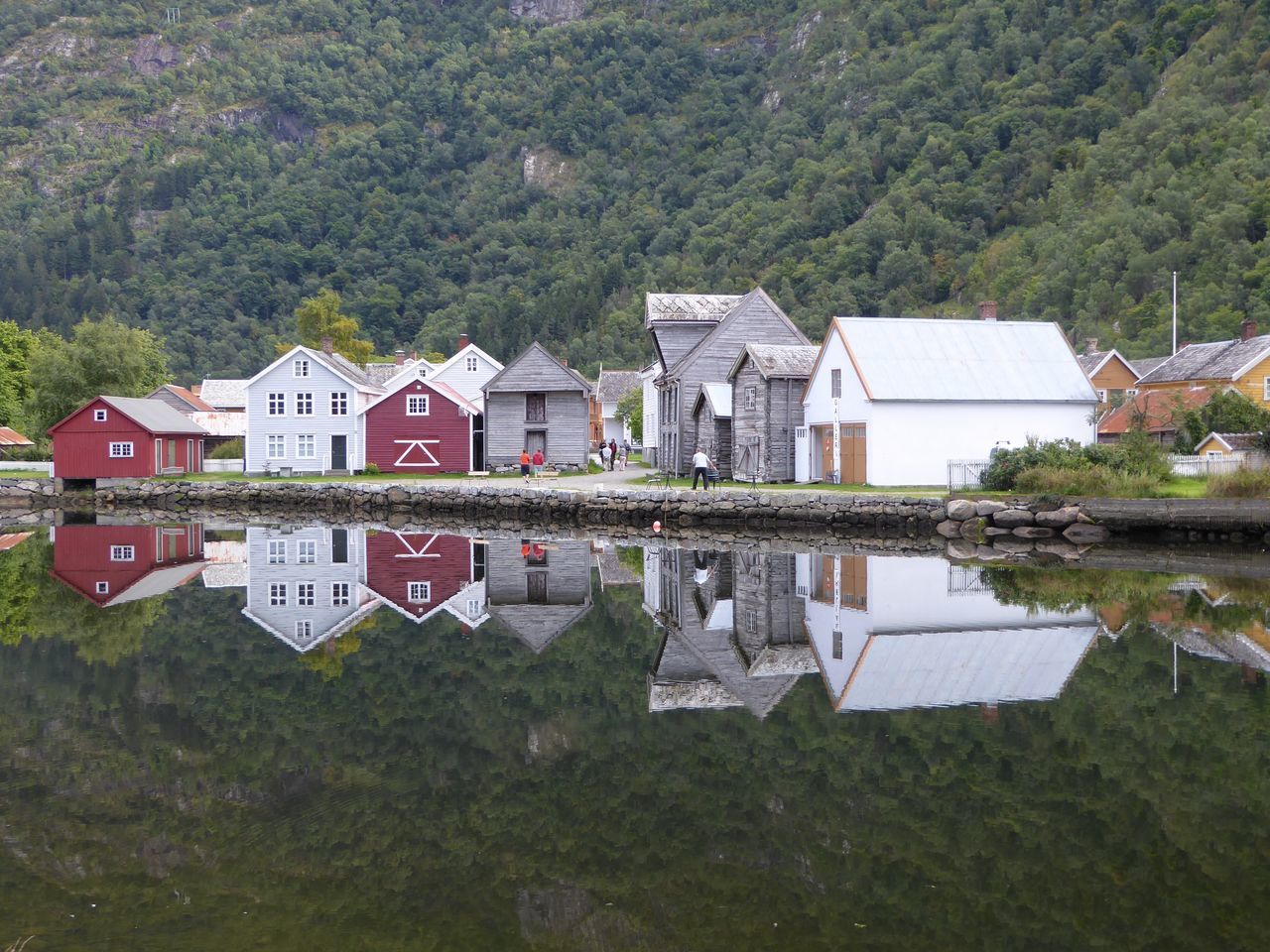 architecture, built structure, building exterior, house, water, residential structure, tree, reflection, waterfront, standing water, day, nature, scenics, outdoors, mountain, town, tranquility, no people, green color, small, tranquil scene, residential district, riverbank, remote