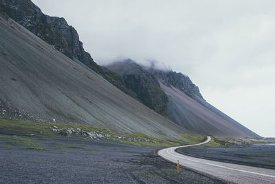 Scenic view of road by mountains against sky