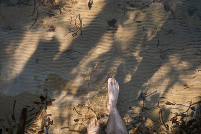 A barefoot man is walking in shallow water. point of view