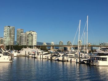 Sailboats moored in harbor against buildings in city