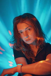 Portrait of young woman against illuminated lights