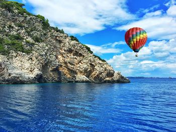 Hot air balloon flying over sea against sky