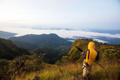 Rear view of man standing on mountain against sky