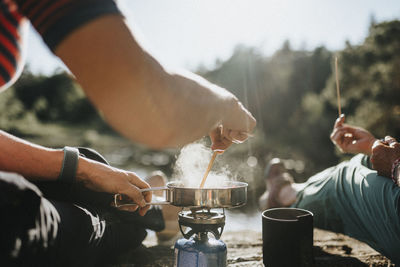 Two senior women preparing hot meal at campsite at lakeshore