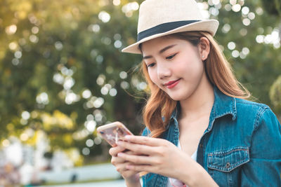 Portrait of smiling young woman using mobile phone outdoors