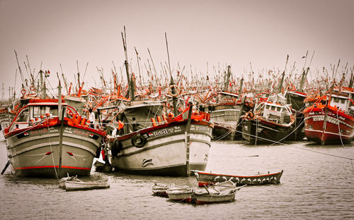 Boats moored at harbor against clear sky