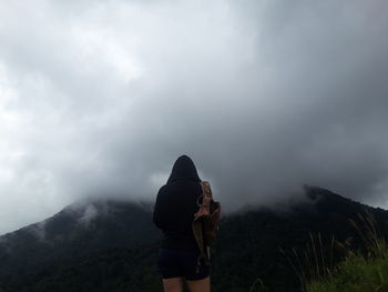 Rear view of people standing on mountain against sky