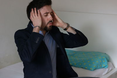 Young man looking away against wall