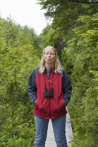 Woman puckering while standing with eyes closed on boardwalk amidst plants at pacific rim national park reserve
