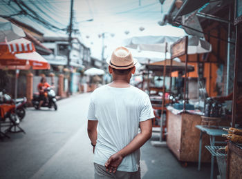 Rear view of man standing on street in city