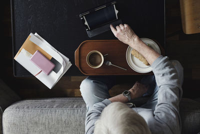 Directly above shot of senior man using digital tablet while having breakfast at home
