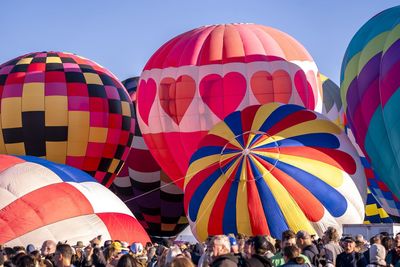 Colorful balloons inflate against a blue sky while spectators watch in albuquerque new mexico, 2022