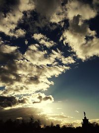 Low angle view of silhouette trees against cloudy sky