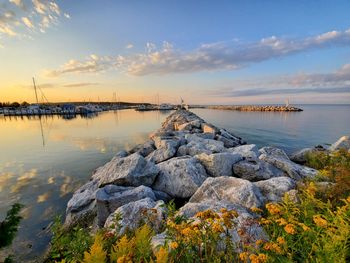 Rocks by beautiful lake against sky during sunset