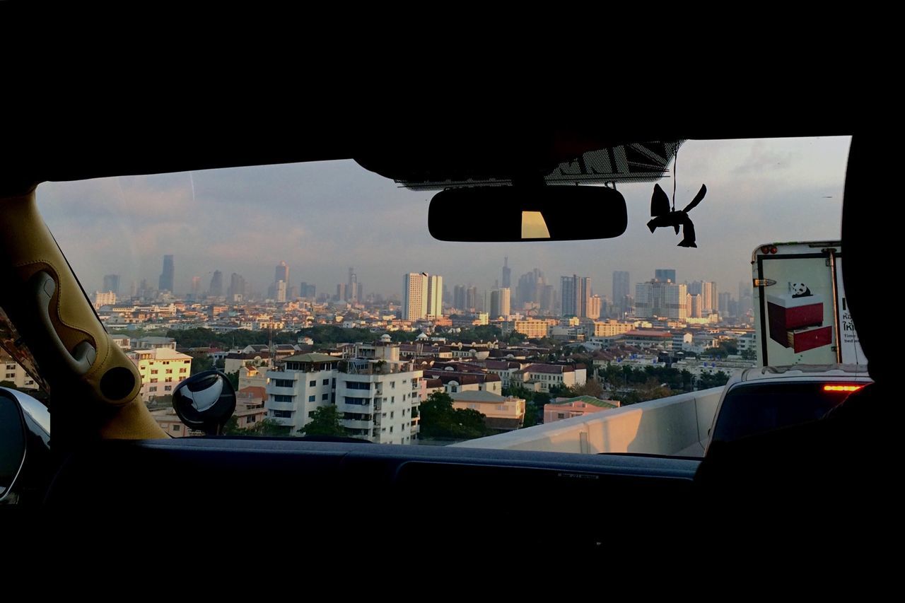 indoors, window, city, cityscape, transportation, transparent, glass - material, architecture, mode of transport, vehicle interior, built structure, sky, building exterior, airplane, crowded, travel, reflection, air vehicle, city life, car