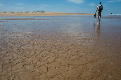 Low section of man on shore against sky