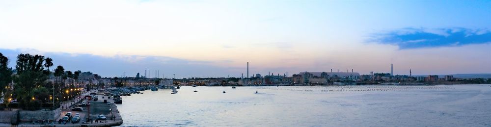 Panoramic view of sea and buildings against sky at sunset