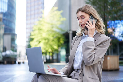 Businesswoman using mobile phone while sitting in office