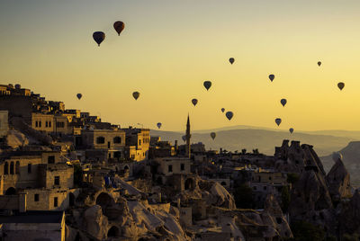 Hot air balloons flying over buildings in city during sunset