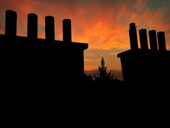 Silhouette built structure against orange sky