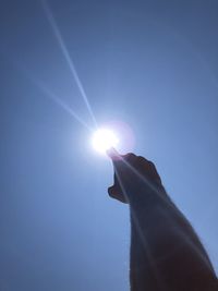 Low angle view of hand against bright sun