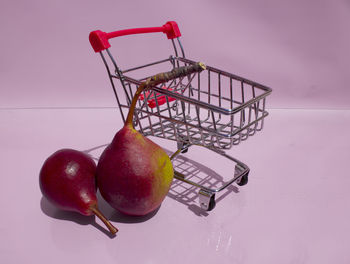 Close-up of apples in basket on table against wall