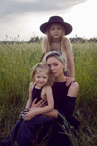 Mother in an evening dress and a retro camera with two daughters. green field with grass in  summer